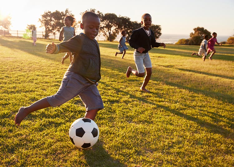 Elementary school kids playing football in a field